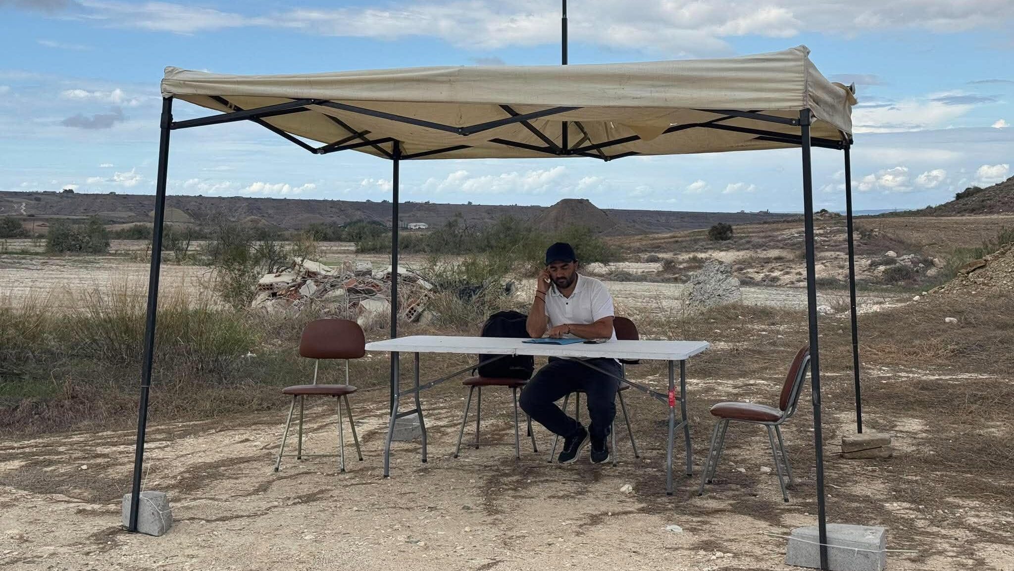 VIDEO: Under an awning outside the asphalt plant, Community Leader Mitseros set up his… office